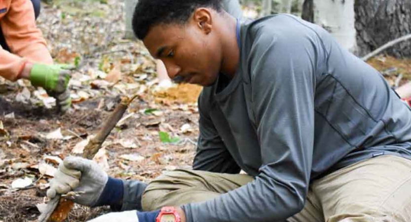 a person does work on a trail as part of a service project with outward bound